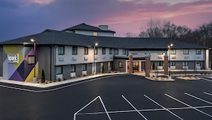Een hotel met een modern design, voorzien van een ruime parkeerplaats en een goed verlichte ingang.