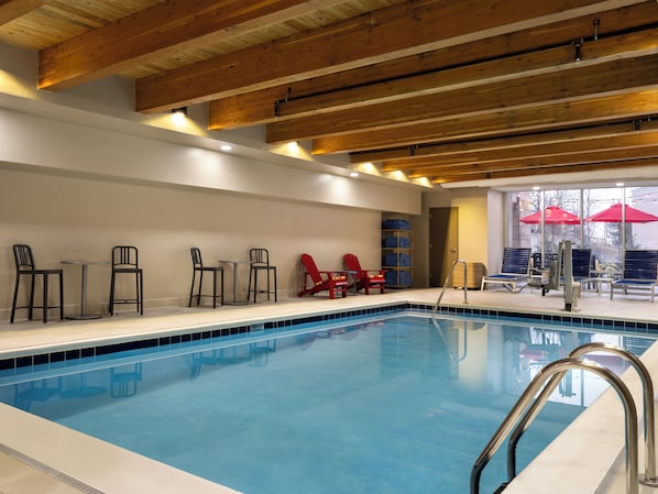 An indoor swimming pool with wooden beams, lounge chairs, and a sun umbrella. - Tru By Hilton Norwalk Des Moines (Norwalk)