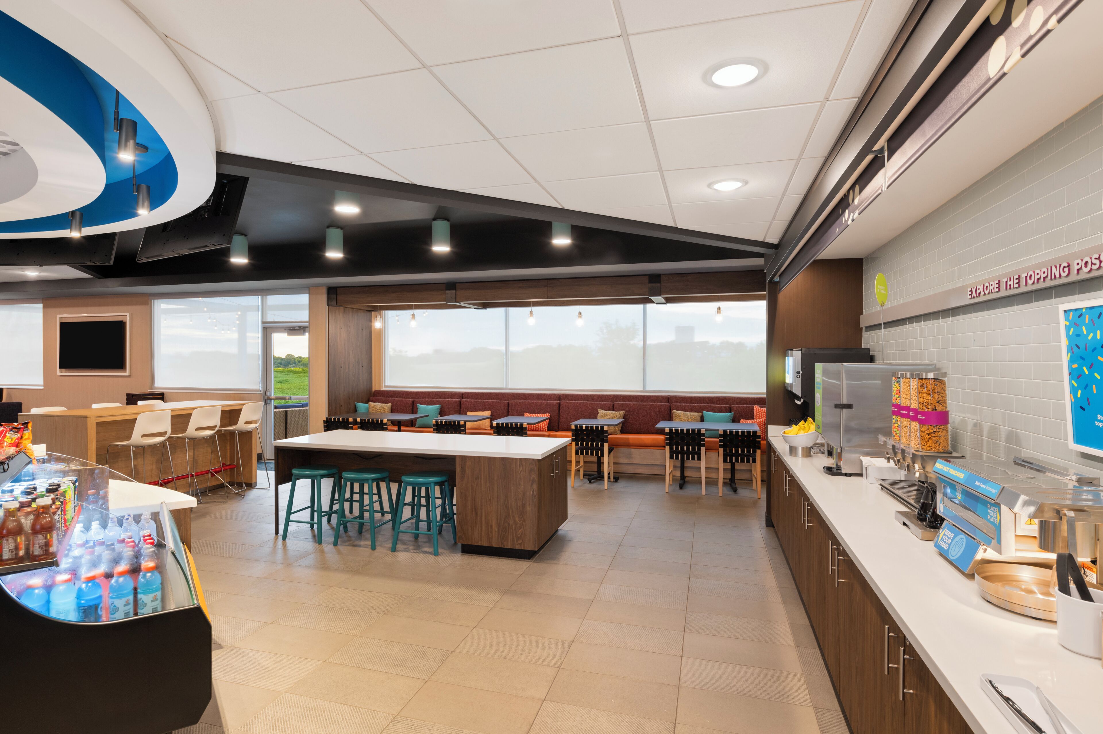 A modern cafe with a central island, seating area, and a counter with a menu display.