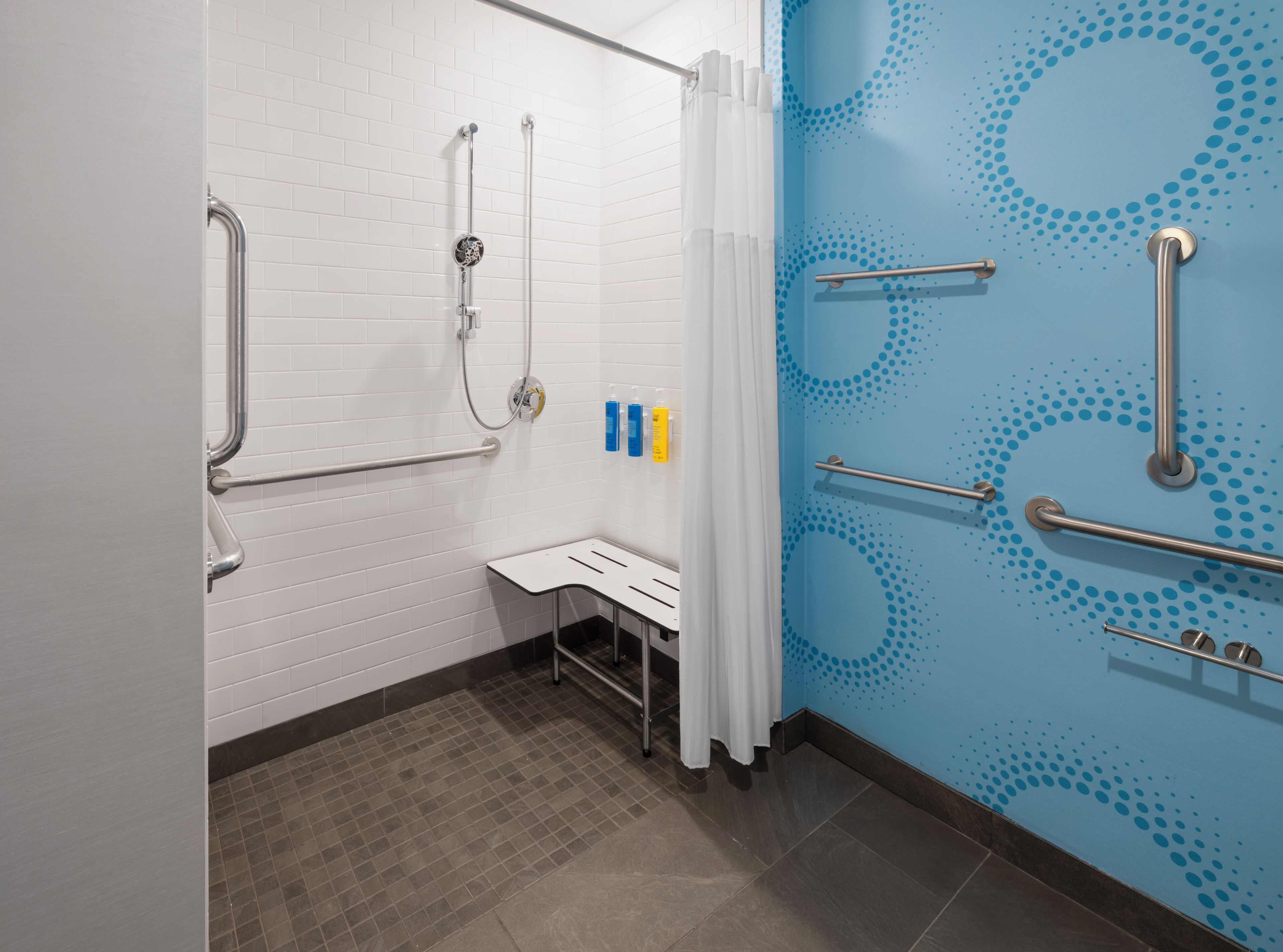A bathroom with white tiled walls, a blue patterned wall, and a bench.