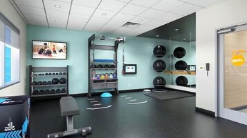 Un gimnasio moderno con equipo de ejercicio, un televisor montado en la pared y un espejo.