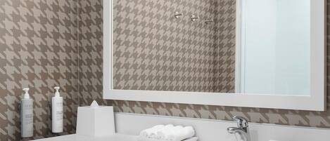 A bathroom with a houndstooth patterned wall, a white sink, a mirror, and a towel rack.