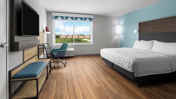 Habitación de hotel con cama, escritorio, silla, televisor y ventana con vistas.