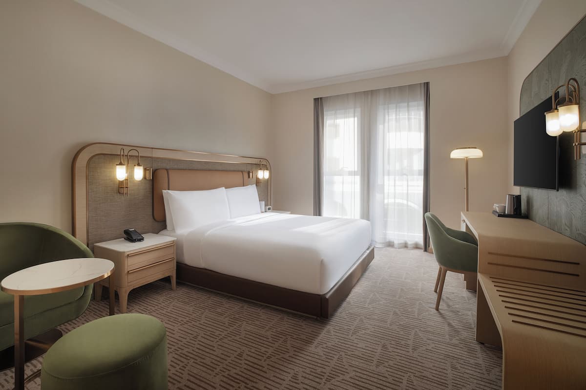 Una habitación de hotel con una cama, mesitas de noche, un escritorio, una silla y un televisor.