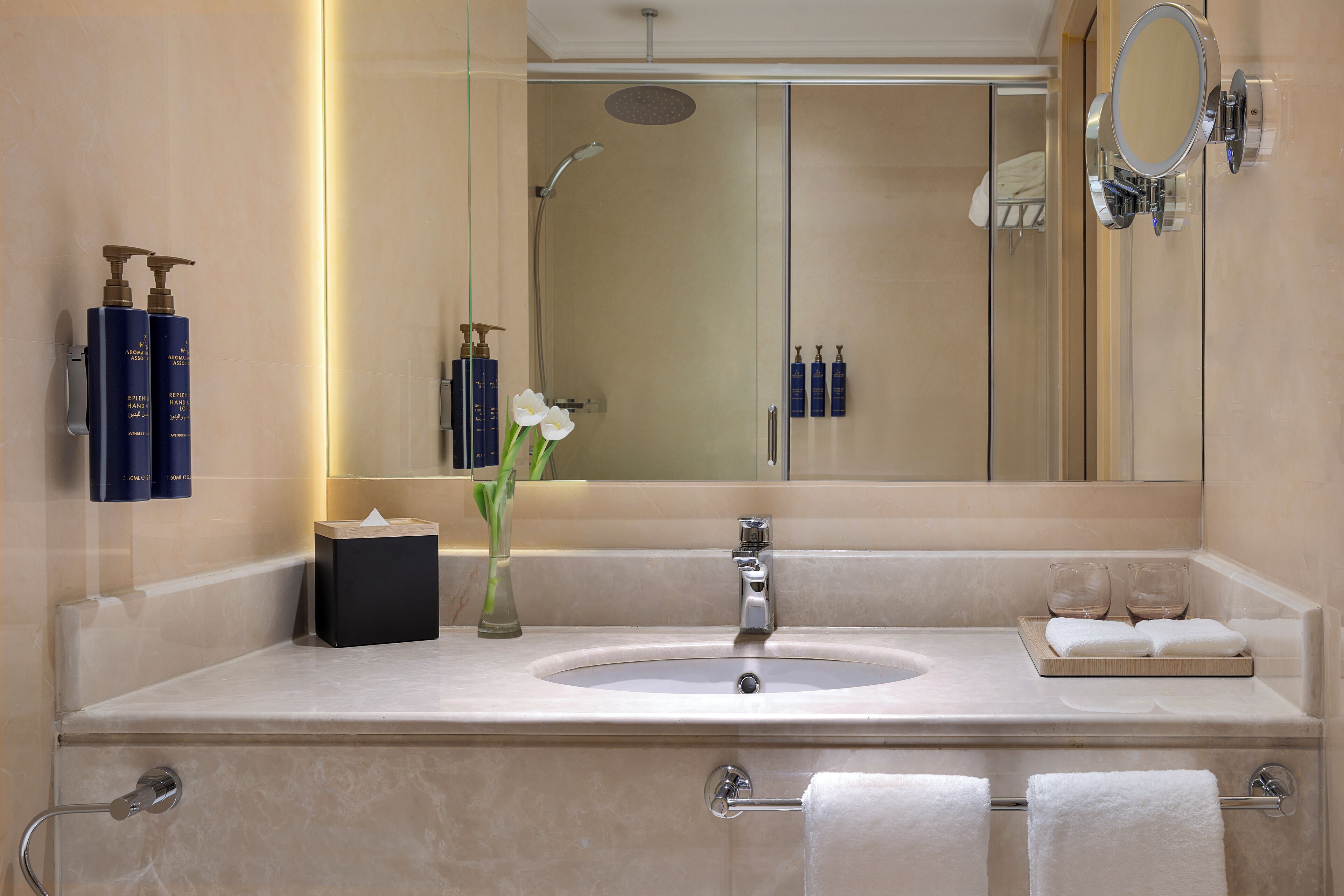 A modern bathroom with a large mirror, a sink, and a shower.