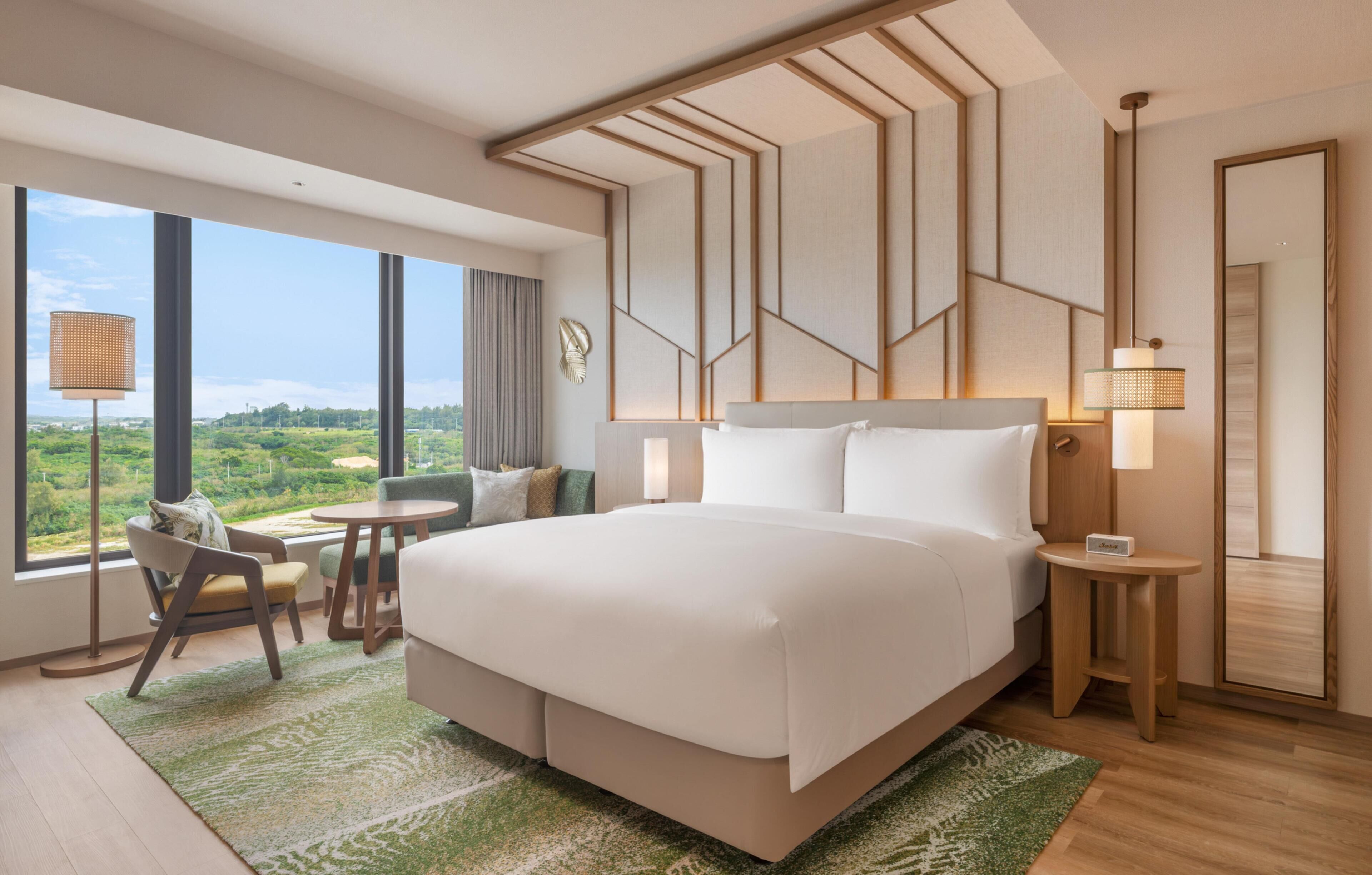 Une chambre d’hôtel moderne, dotée d’un grand lit, d’un bureau, d’une chaise et offrant une vue sur l’extérieur.