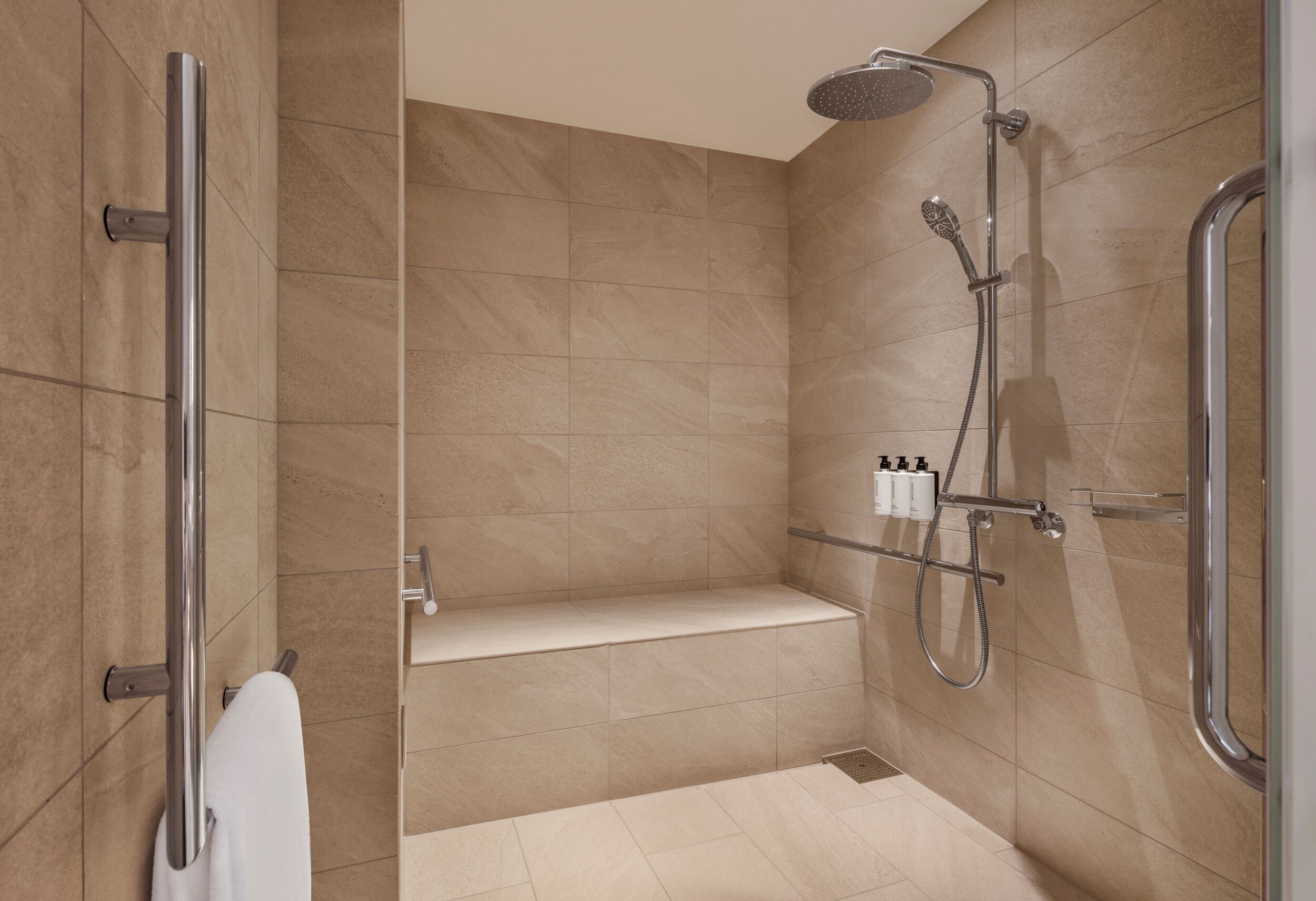 Une salle de bain moderne équipée d’une douche, d’un banc et d’un porte-serviettes.