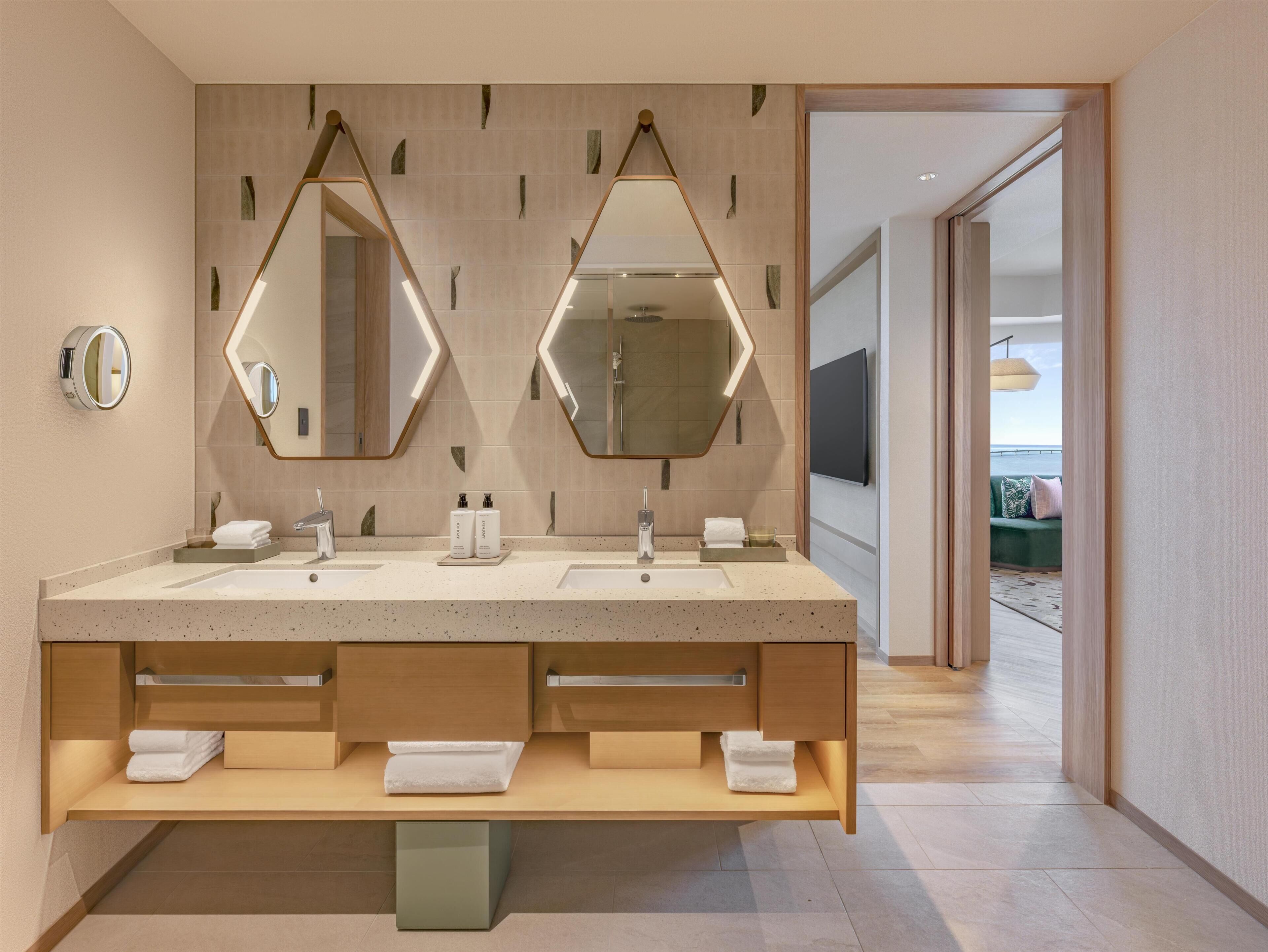 A modern bathroom with two sinks, a large mirror, and a vanity with storage.
