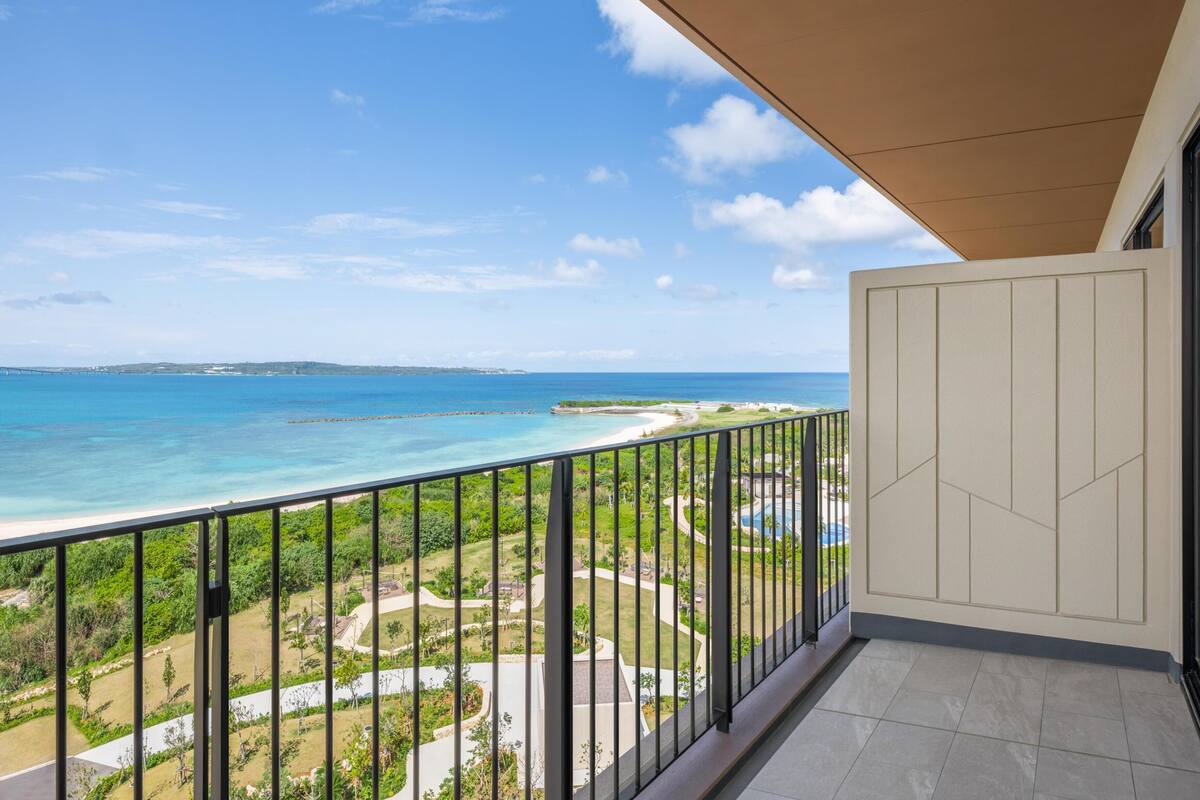 A balcony with a view of a beach and a clear sky.