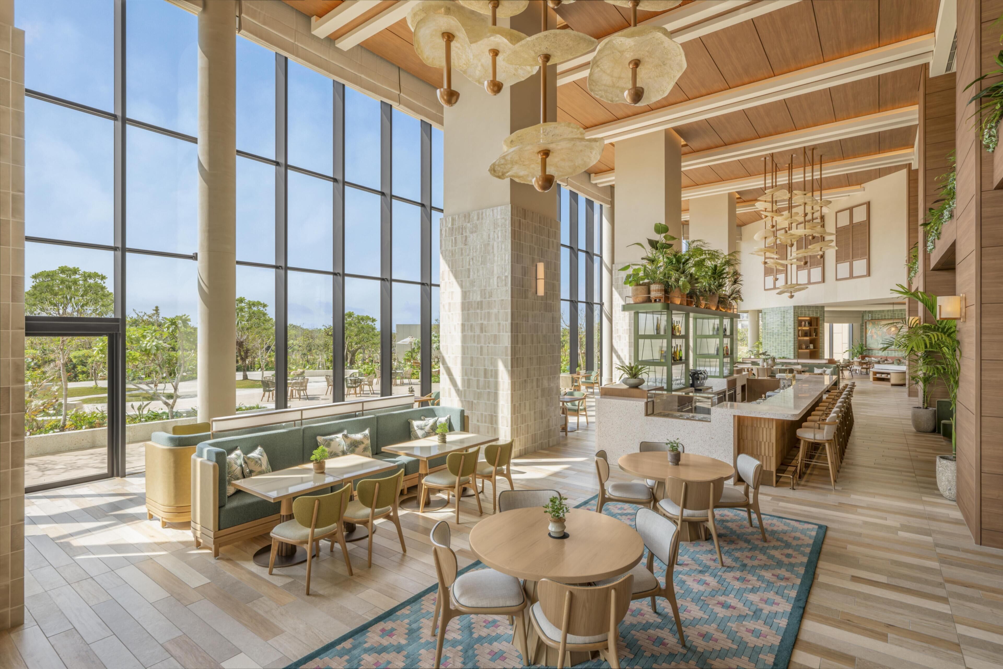 A spacious indoor area with large windows, multiple seating arrangements, and a kitchen area.