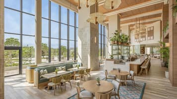A spacious indoor area with large windows, multiple seating arrangements, and a kitchen area.