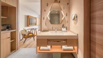 Une salle de bain moderne avec un lavabo sur pied, un miroir à cadre géométrique et des meubles en bois.