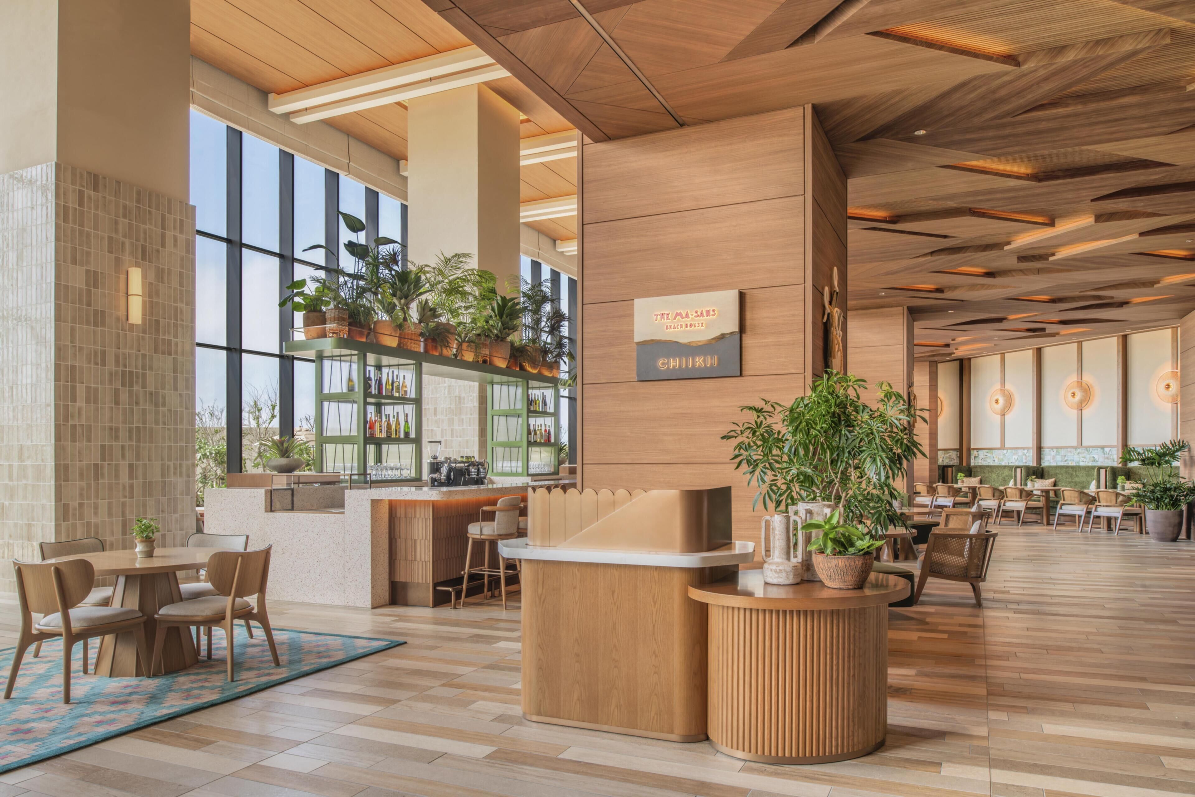 Um hall amplo com balcão de recepção, área de estar e bar com plantas.