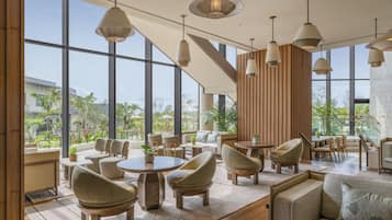 Een modern interieur met grote ramen, houten meubels en hanglampen.
