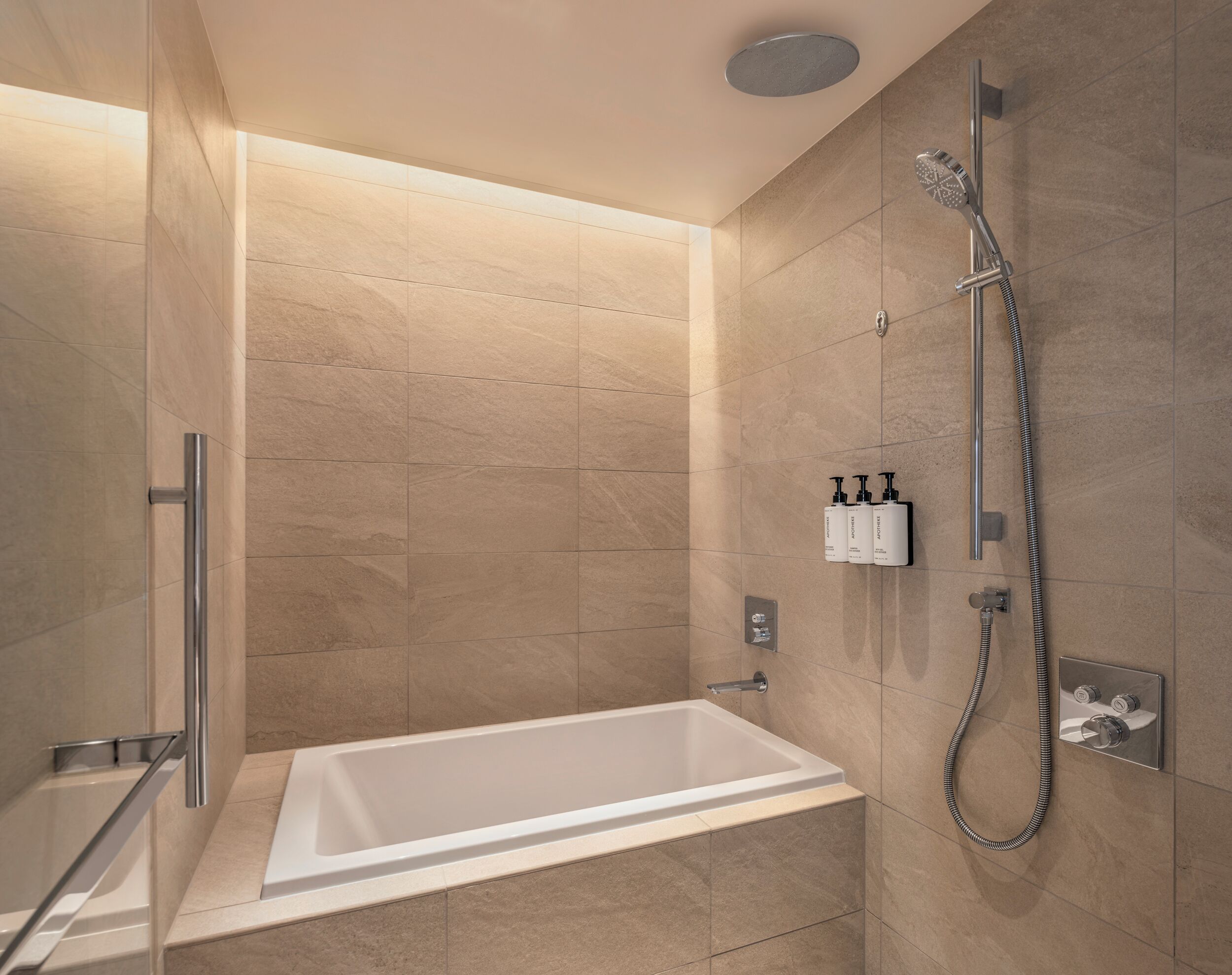 A modern bathroom with a bathtub, shower, and hand sanitizer dispensers.