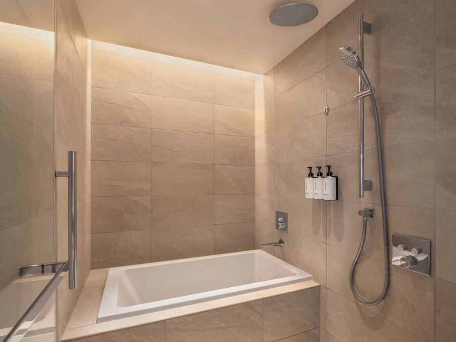 A modern bathroom with a bathtub, shower, and hand sanitizer dispensers.