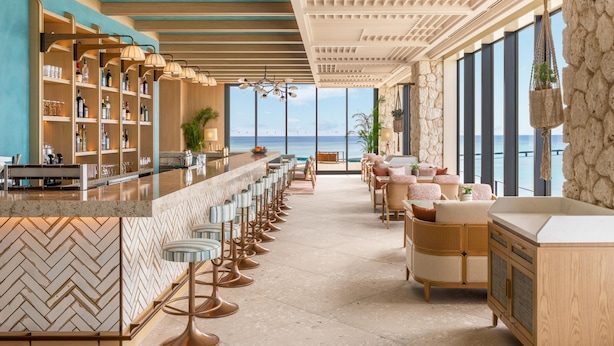 A bar area with a long counter, bar stools, and a view of the ocean. - Canopy By Hilton Okinawa Miyako Island Resort (Miyakojima)