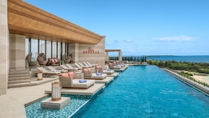 A poolside area with lounge chairs and a view of the sea. - Canopy By Hilton Okinawa Miyako Island Resort (Miyakojima)