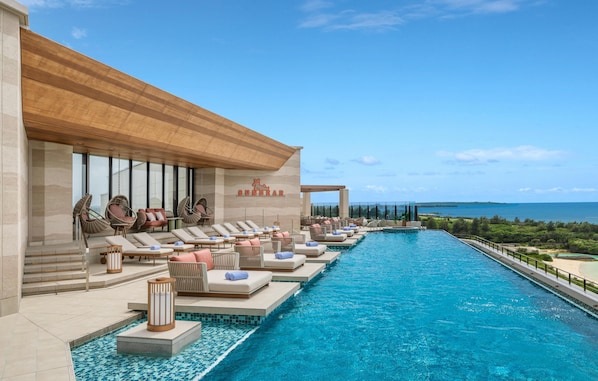 A poolside area with lounge chairs and a view of the sea.