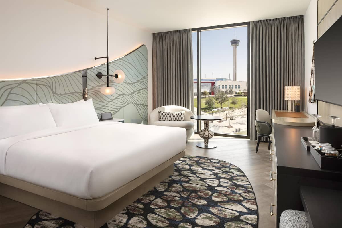 Habitación de hotel con una cama grande, un escritorio, una silla y vistas a una torre.