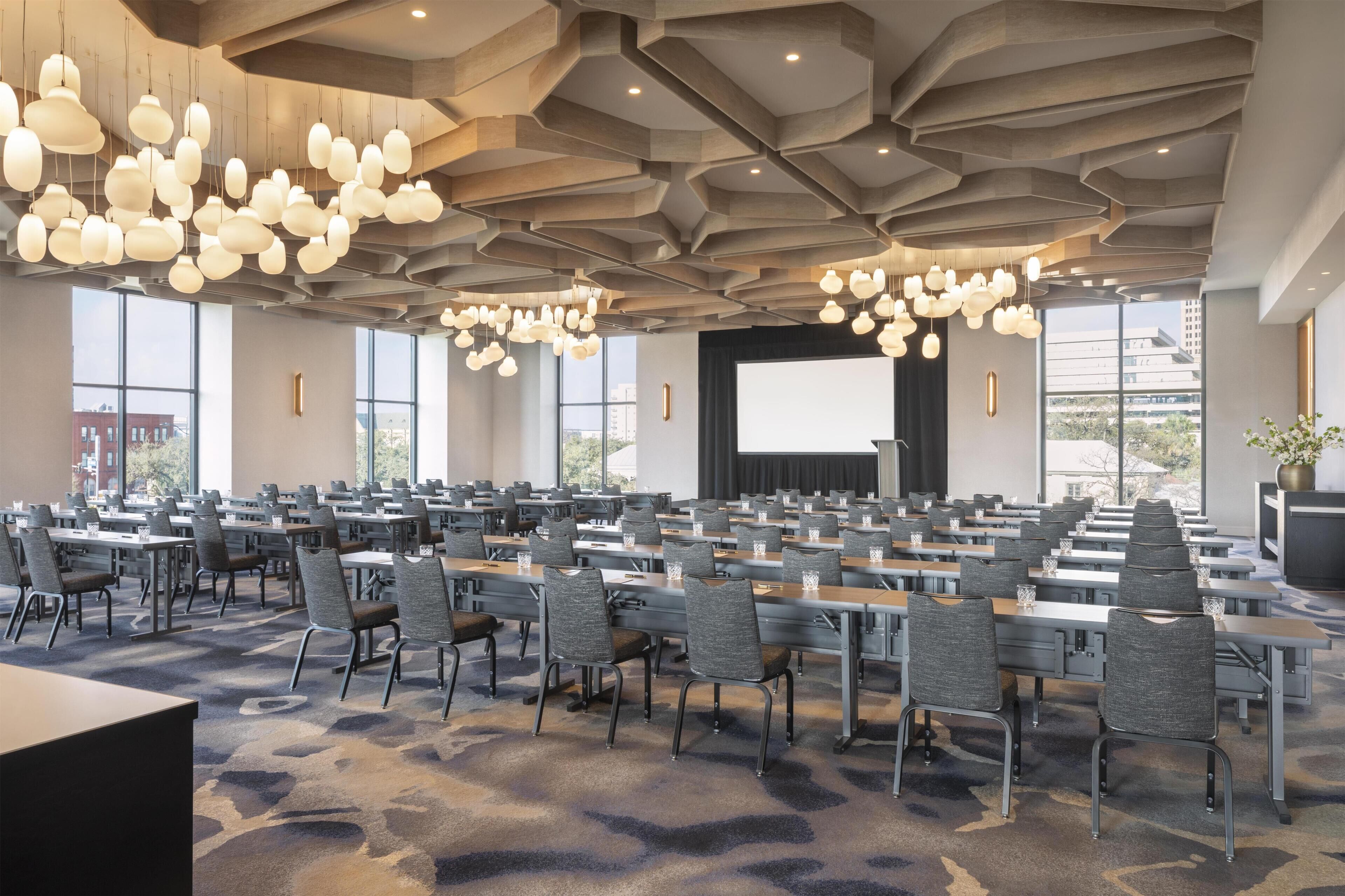Una sala conferenze con diversi tavoli e sedie, ampie finestre e un moderno design del soffitto.