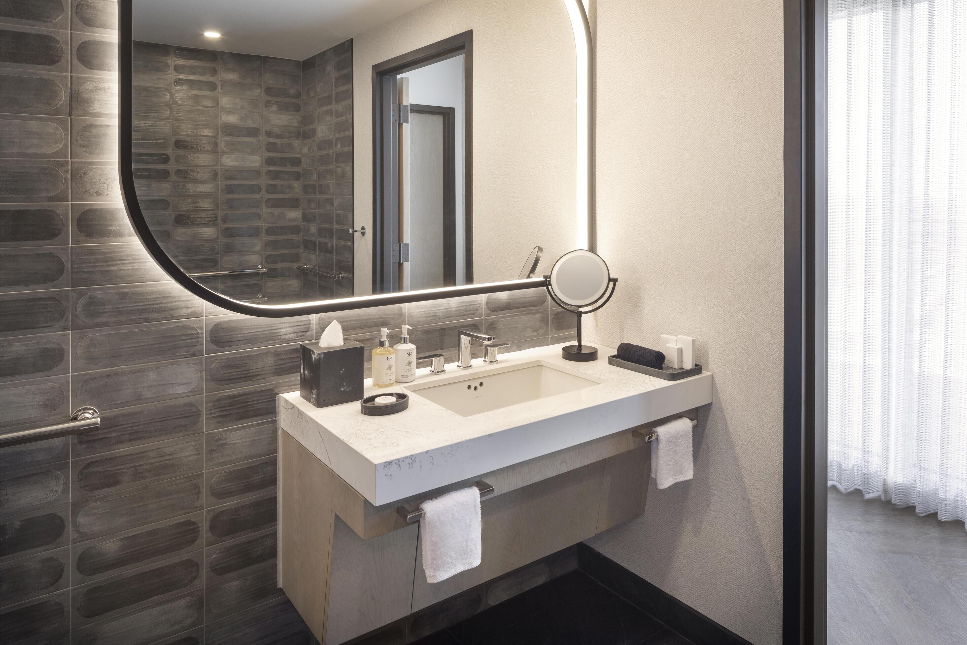A modern bathroom with a double sink, a mirror, and a towel rack.
