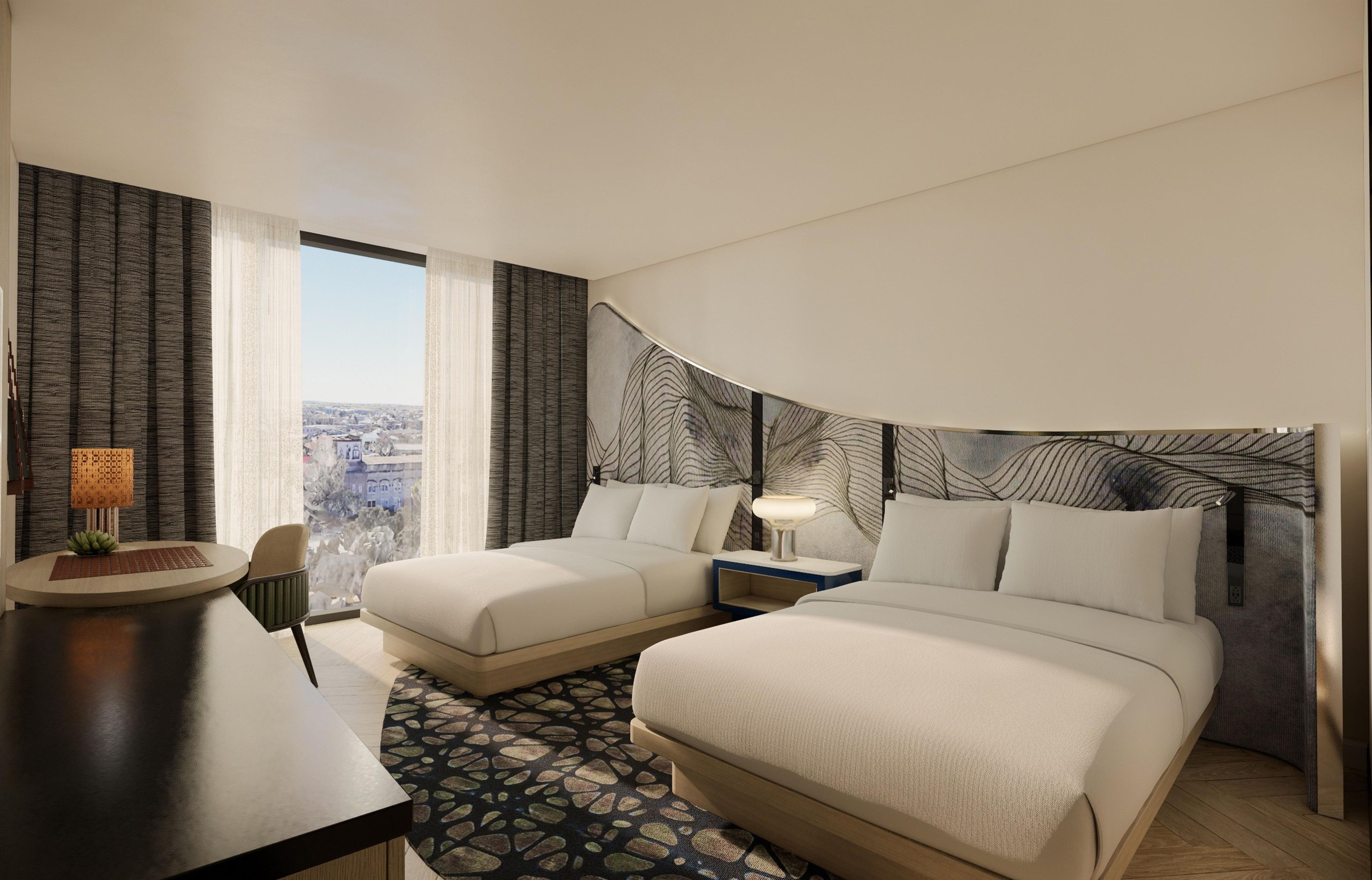 A hotel room with two beds, a desk, a chair, a lamp, and a view of the city.