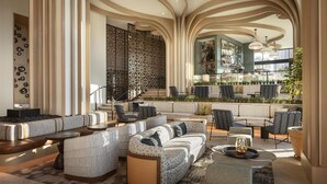 Amplia sala de estar con diseño moderno, que incluye un gran espacio con sofás y sillones, una zona de bar con mostrador y vistas al patio exterior.