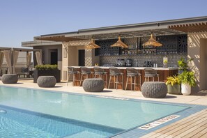 Ein Barbereich am Pool mit Sitzgelegenheiten und einer Theke, umgeben von einem Schwimmbecken.