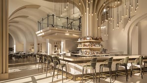 Un amplio bar con techos altos y luces colgantes, una barra central y diversas opciones de asientos.