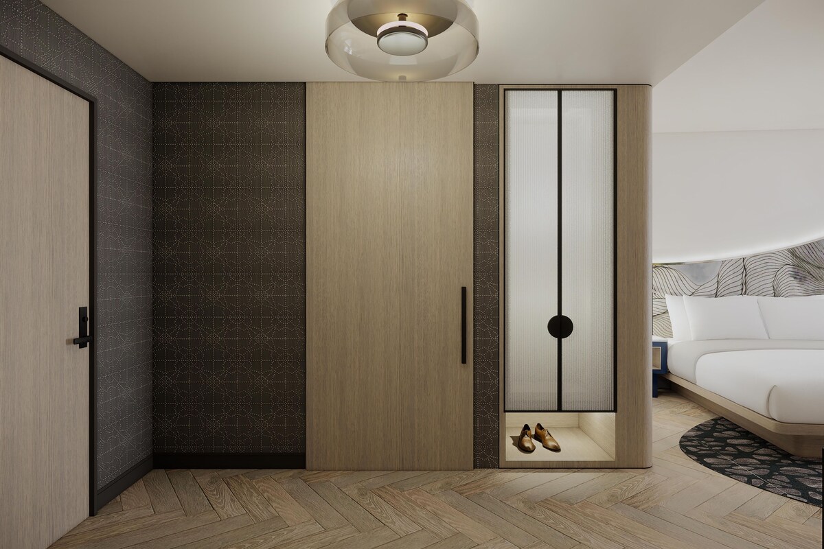 Een moderne slaapkamer met een houten garderobe, een bed en een plafondlamp.