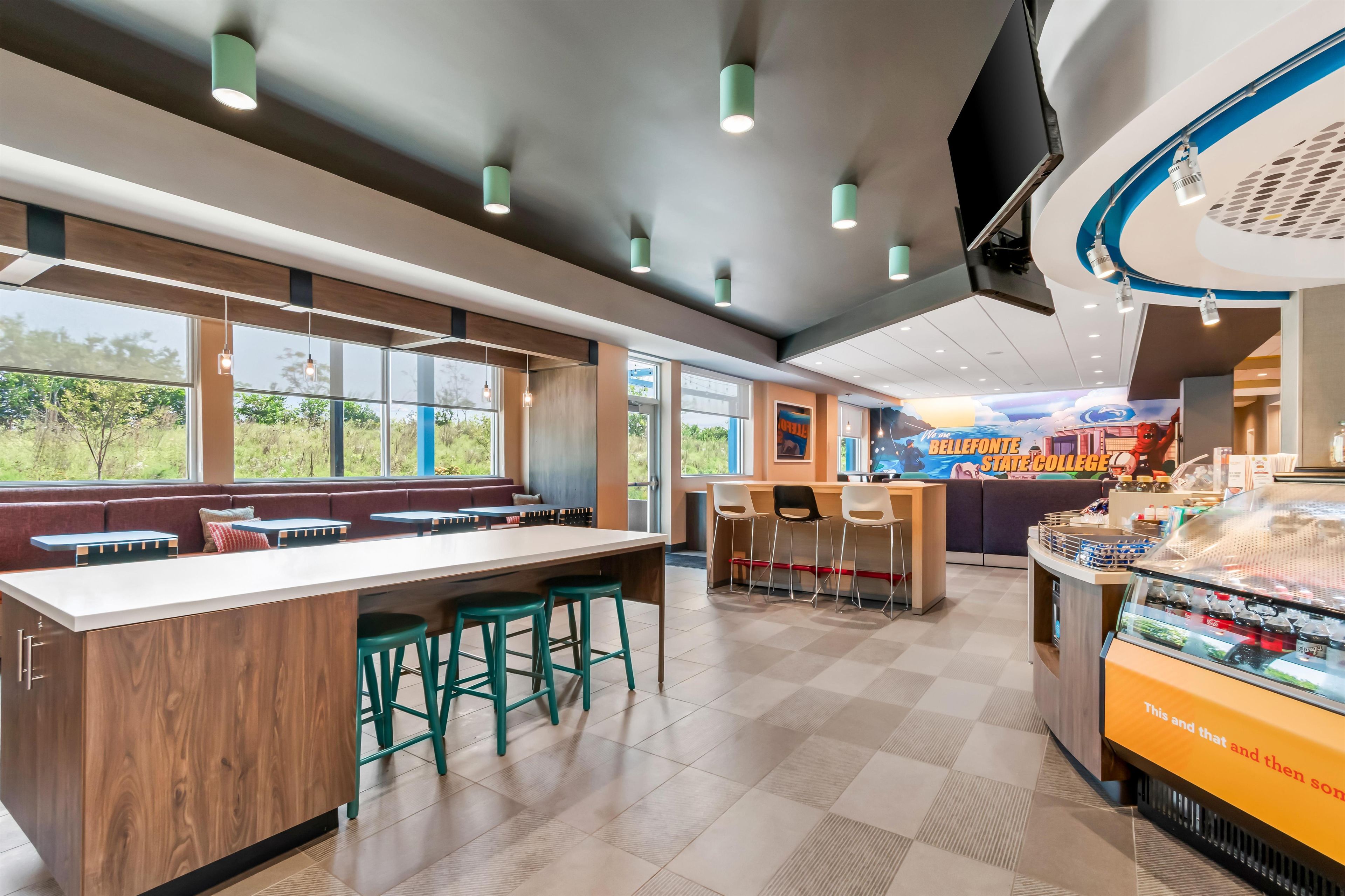 L’intérieur d’un café moderne, avec un long comptoir, un espace salon et une fresque murale sur le mur du fond.