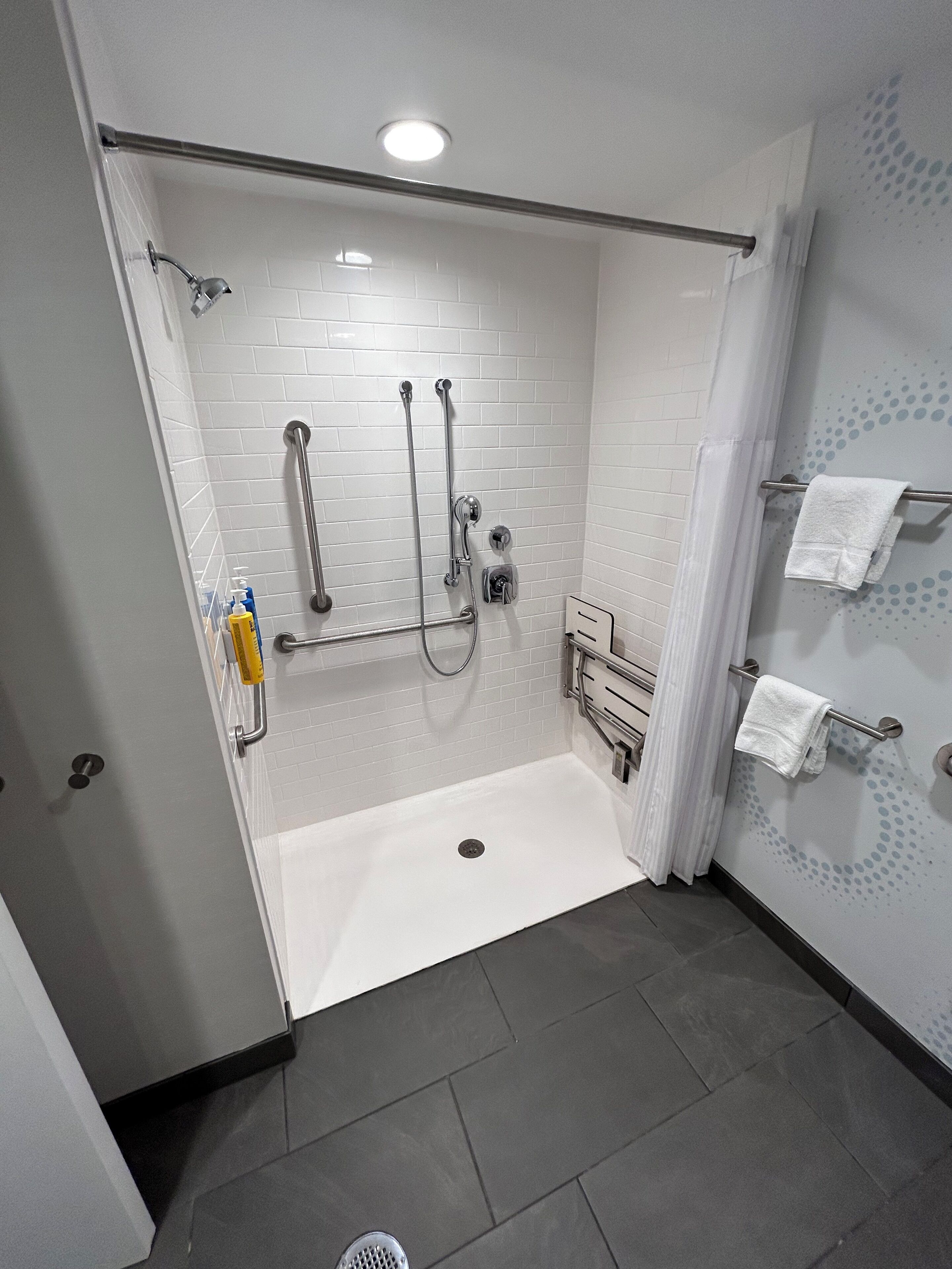 Un baño moderno con ducha a ras de suelo, perchero y secamanos.