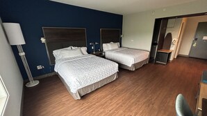 Een hotelkamer met twee bedden, een bureau, een stoel en een lamp.