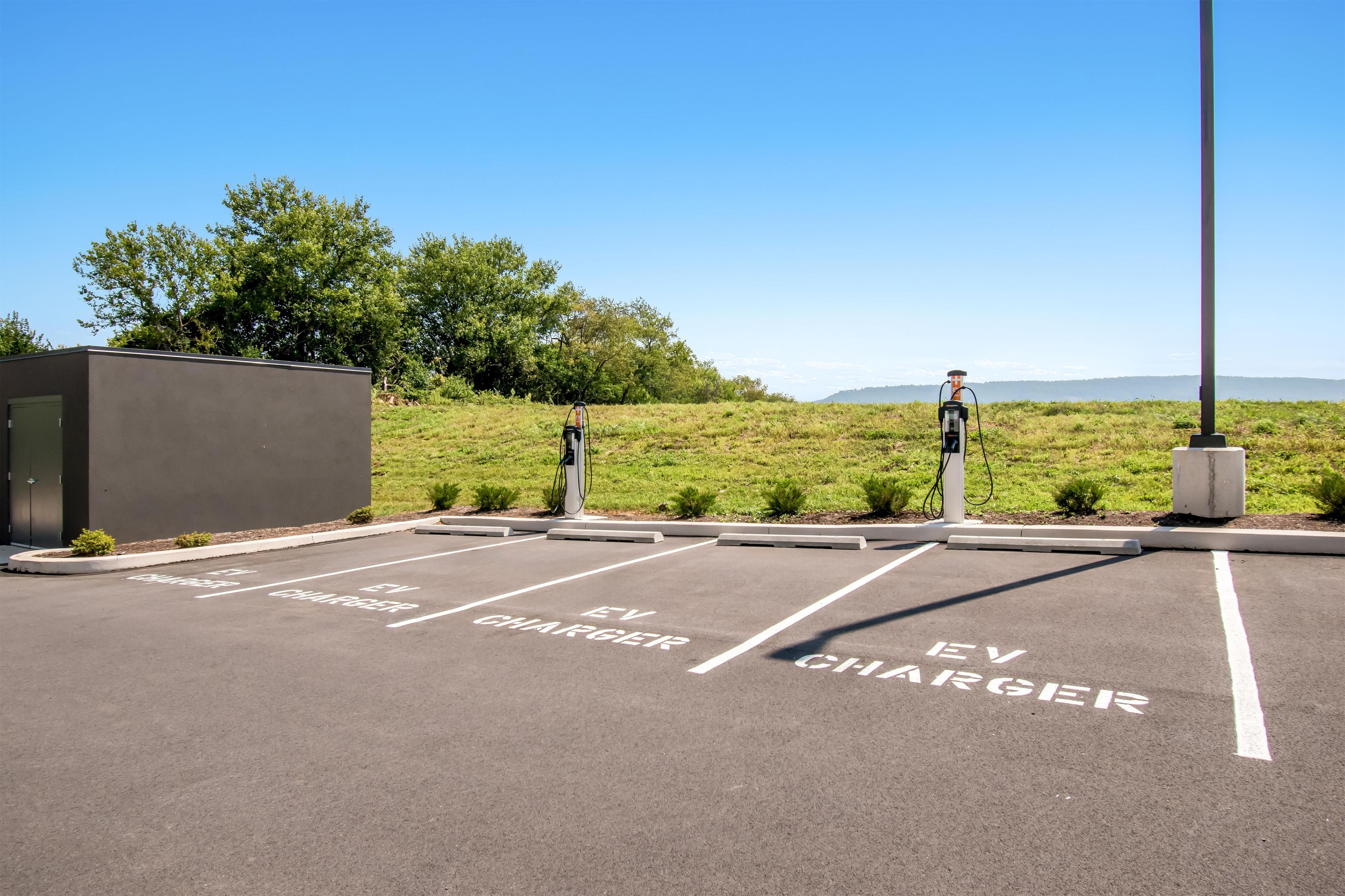 An EV charging station area with designated parking spaces and a small building.