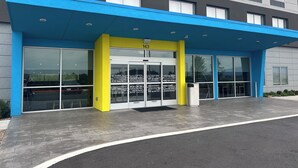 Un edifici modern amb façana blava i grisosa, grans finestres de vidre i una entrada ben visible.