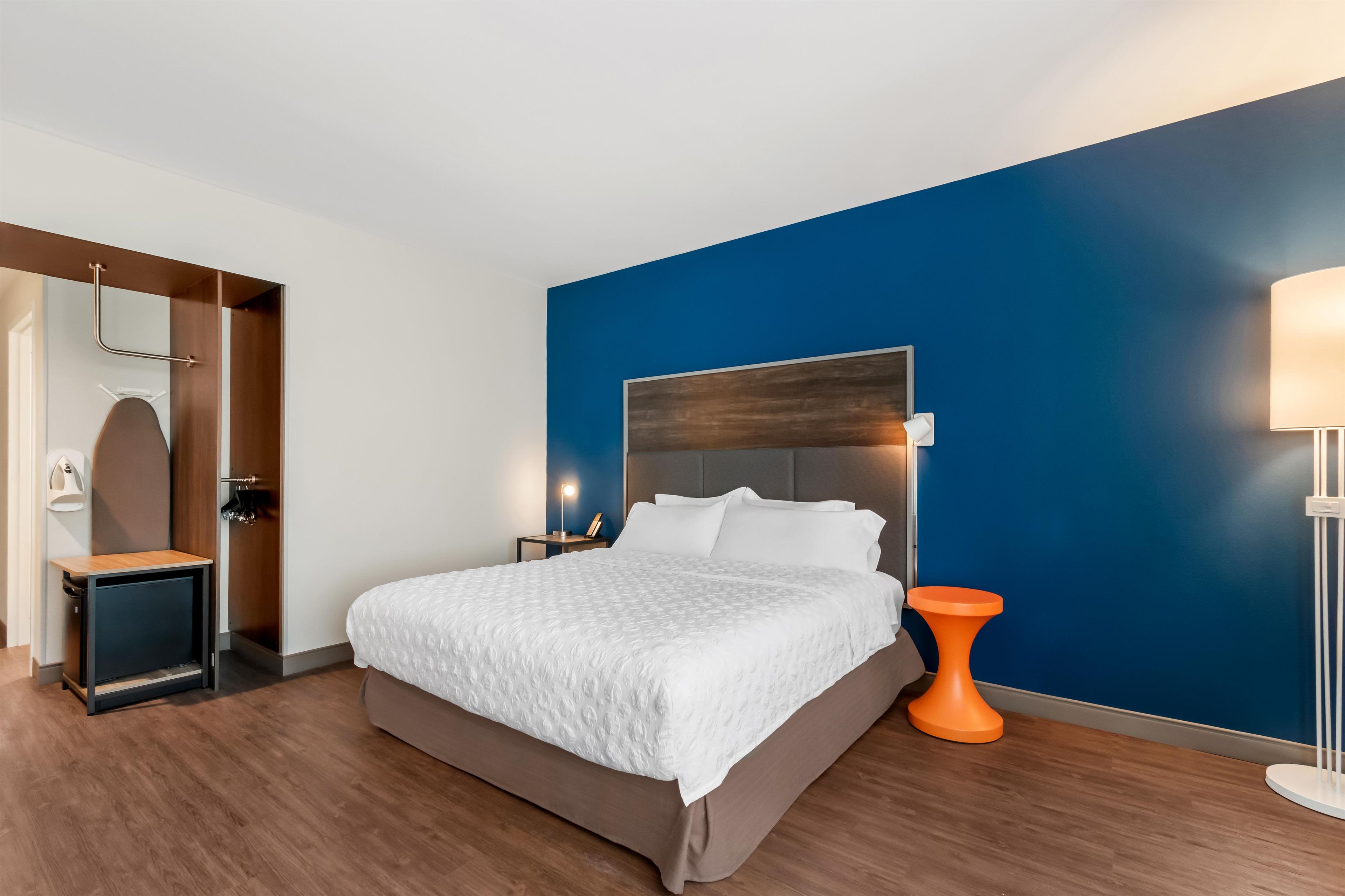 Une chambre d’hôtel moderne avec un grand lit, une table de chevet, une lampe de chevet et une lampe fixée au mur.