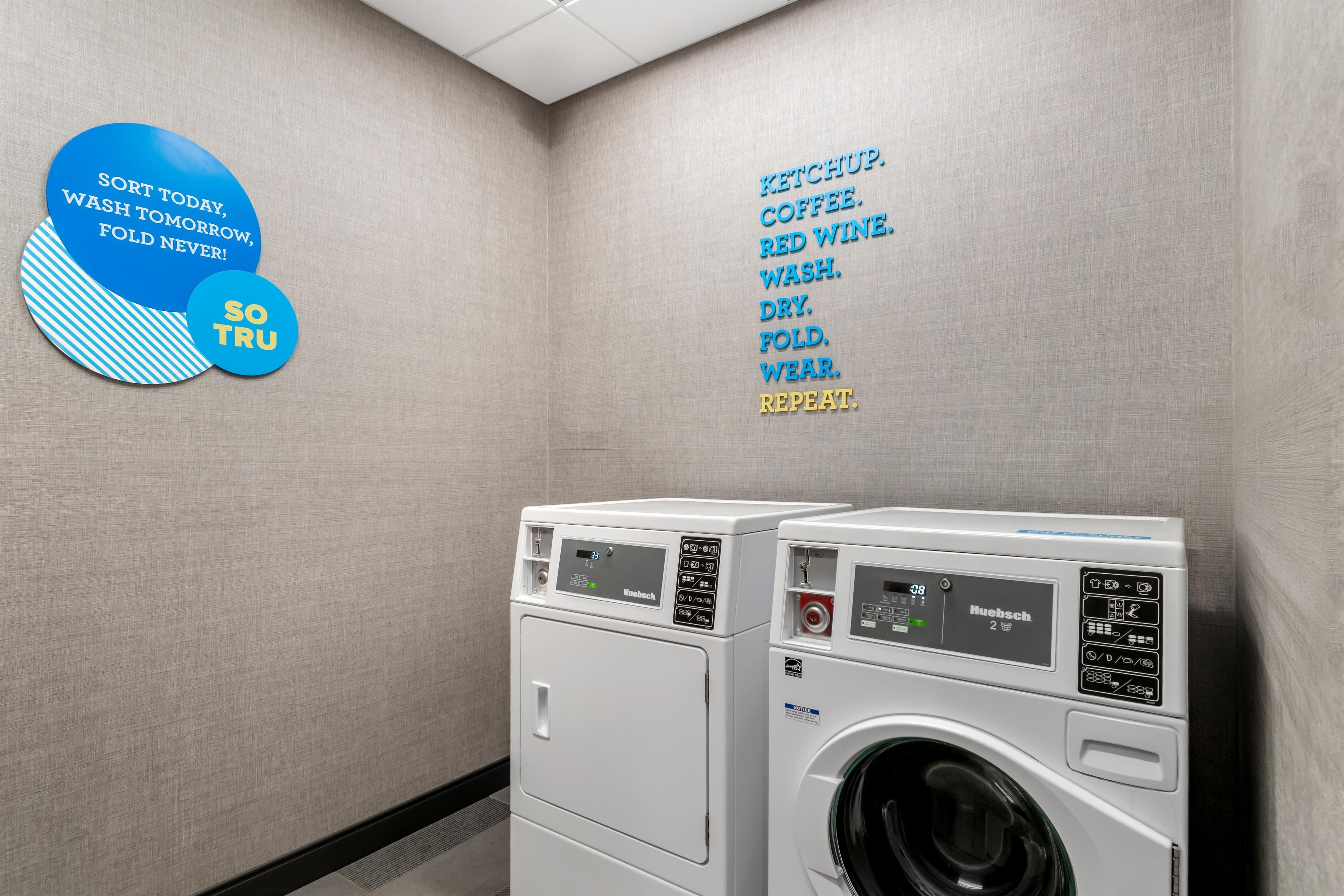 Une buanderie équipée de deux machines à laver à chargement frontal et d’un mur sur lequel sont affichées les instructions de lavage.