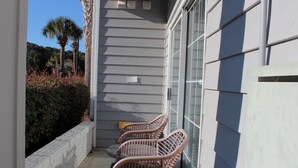 A balcony with wicker chairs, a small table, and a patterned rug. - The Villa at 205 Royal Poste Rd (Sunset Beach)