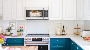 A kitchen with white cabinets, a stainless steel stove, a microwave, and a toaster. - Eclectic 1906 Farmhouse: 2 Acres, Fire Pit, Minutes to Lake Norman  & Charlotte (Huntersville)