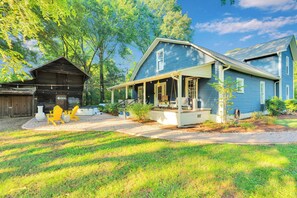 A two-story house with a porch, a covered outdoor seating area, and a wooden barn.