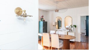A modern dining area with a wooden table, white chairs, and a unique ceiling fan design. - Eclectic 1906 Farmhouse: 2 Acres, Fire Pit, Minutes to Lake Norman  & Charlotte (Huntersville)