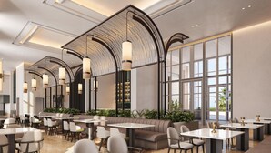 Un hall d’hôtel moderne, doté d’espaces aménagés avec des sièges, des tables et un grand plafond en arc de cercle.