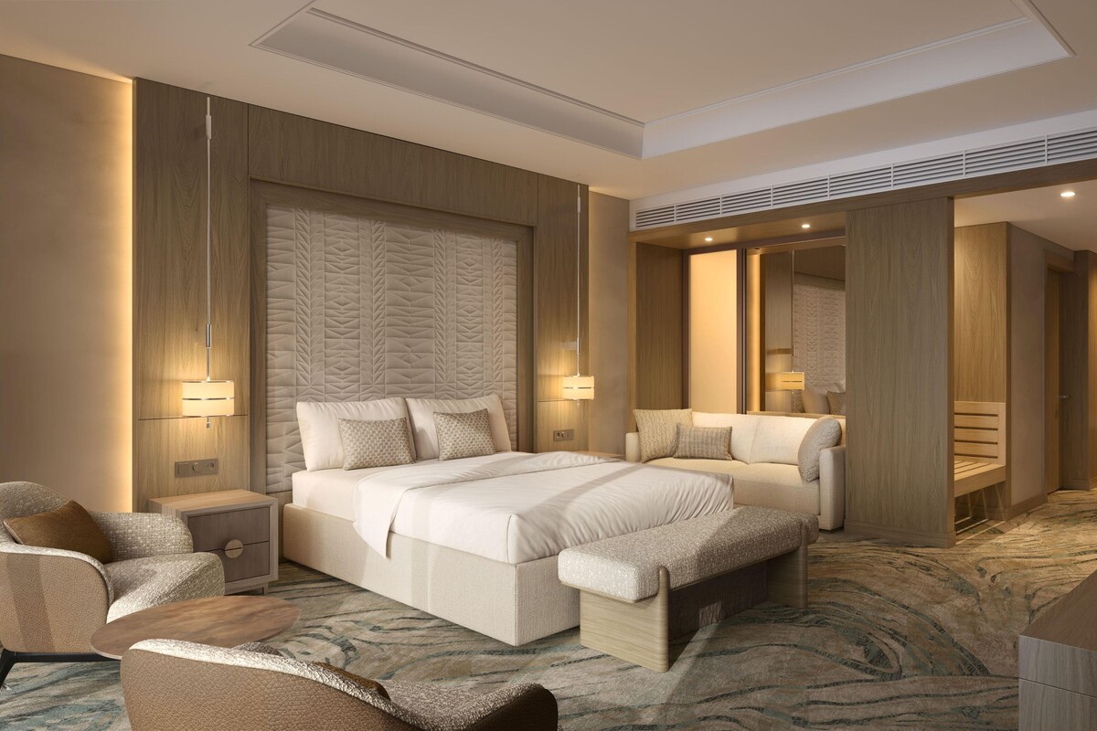 Een hotelkamer met een groot bed, nachtkastjes, een zithoek en een spiegel.