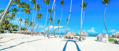 En la playa, playa de arena blanca, camastros y sombrillas