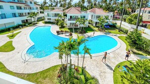 Un resort con una amplia piscina, varias construcciones y palmeras.