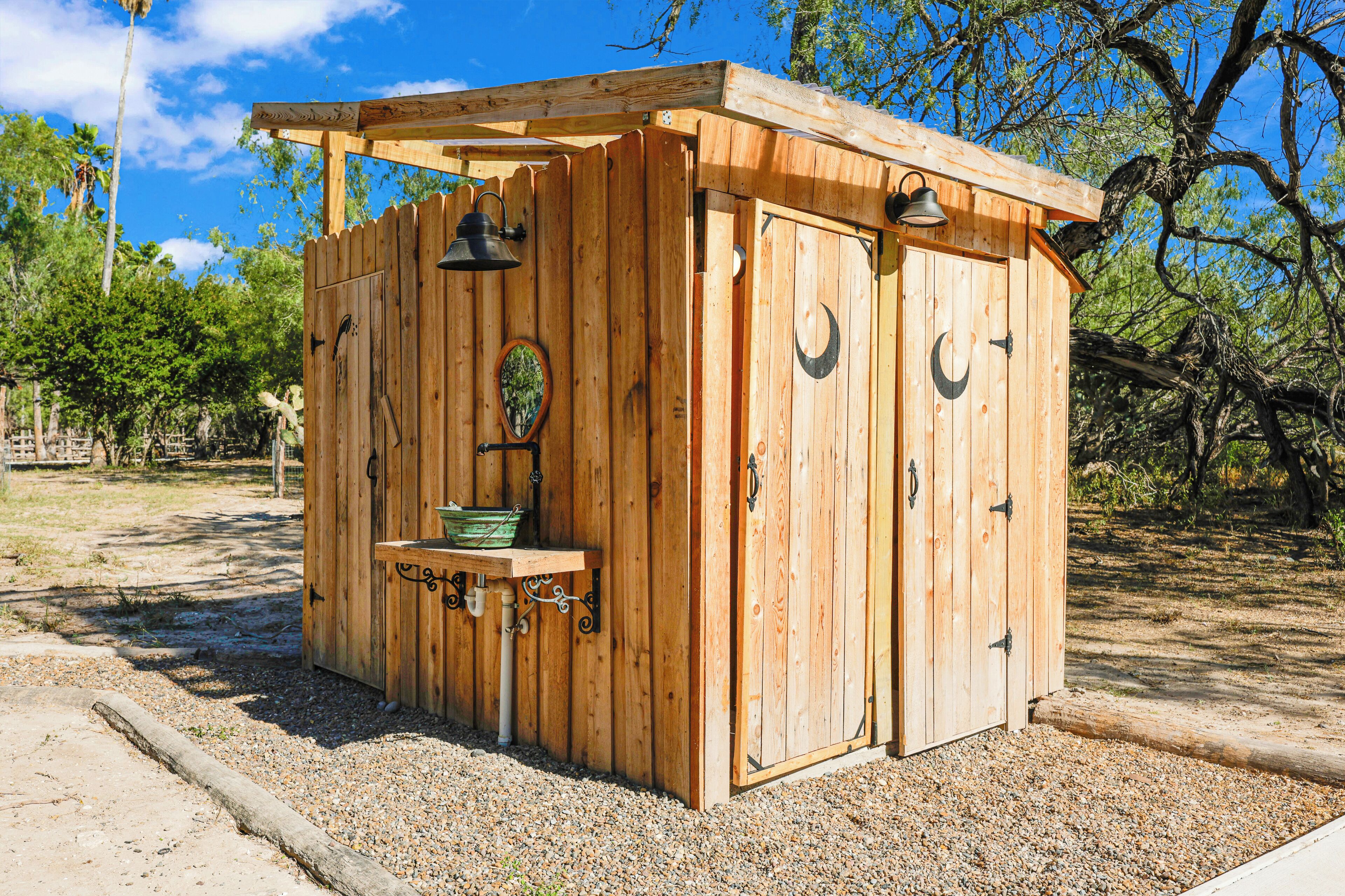 A wooden cabin with a porch, a sink, and a hanging light fixture.