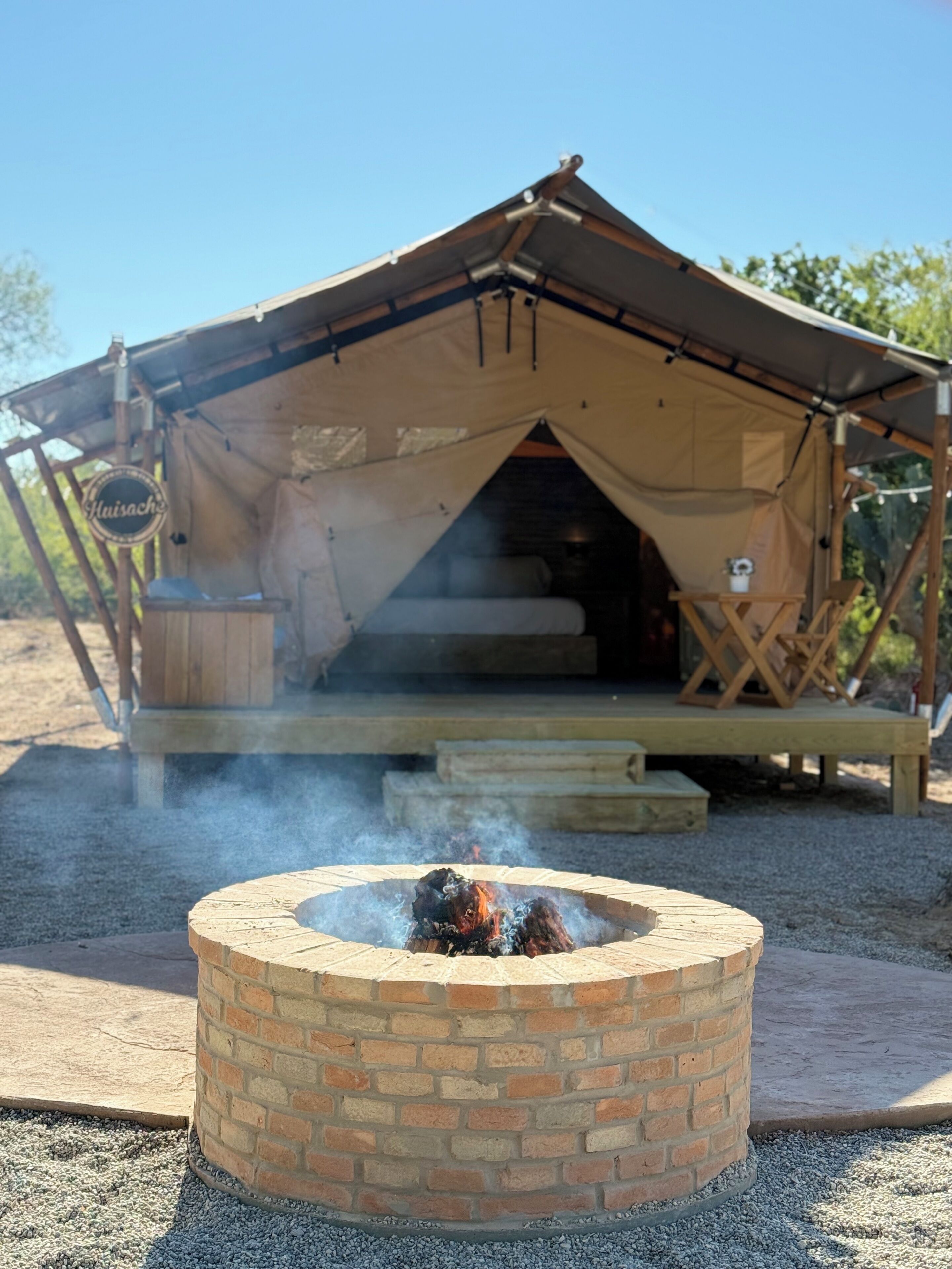 Een tent met een vuurkuil van bakstenen ervoor.