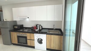 A modern kitchen with white cabinets, a stainless steel refrigerator, a built-in oven, a dishwasher, and a washing machine. - Modern sea view, near Hassan II Mosque, close to town center (Casablanca)