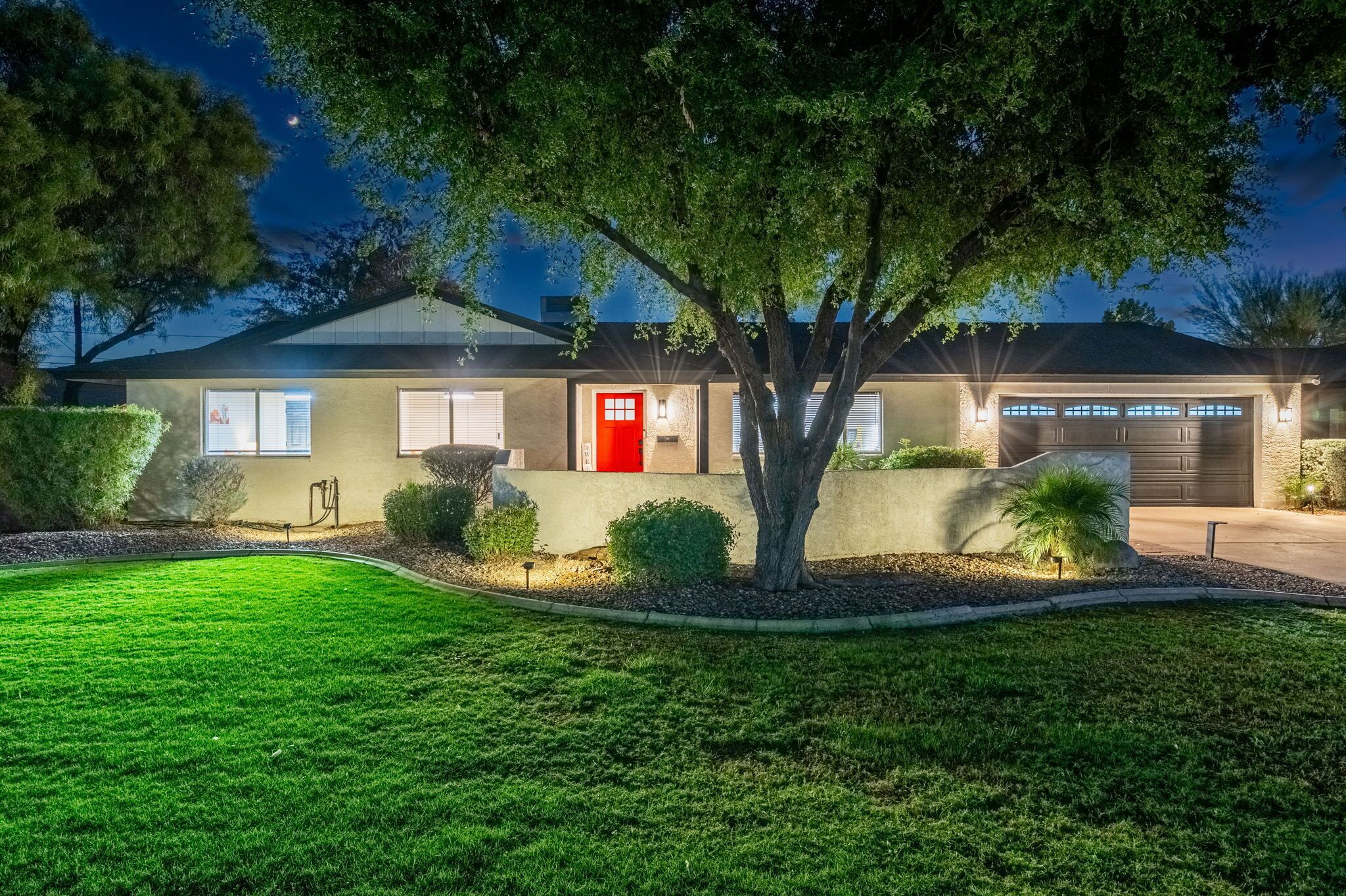 A modern house with a red door, a garage, and a well-maintained lawn.